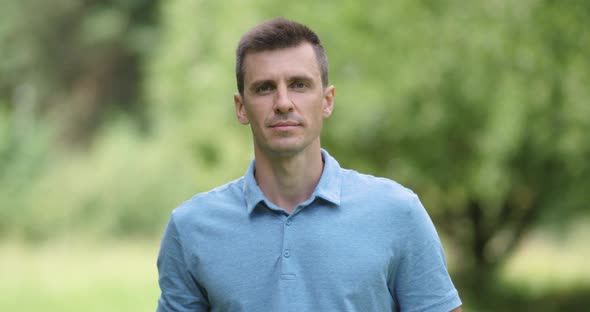 Portrait of an Adult Man on a Blurred Nature Background, a View of a Man's Smiling Face Against a