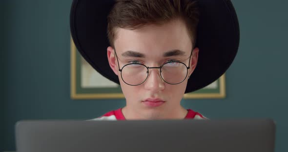 Young freelancer man working on computer typing on laptop. Busy stylish hipster designer.