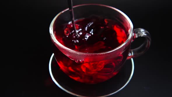 Preparation of Hibiscus tea in a glass cup.