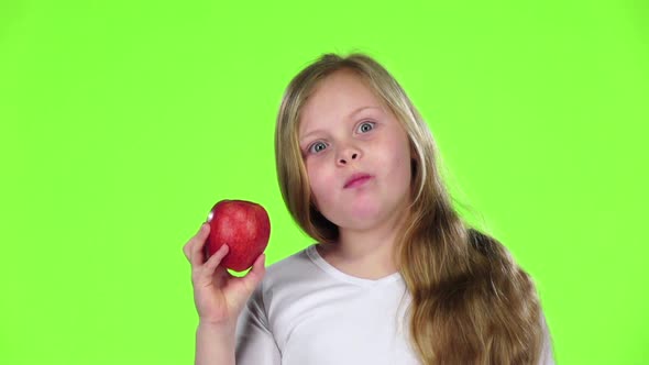 Little Girl Bites an Apple and Shows a Thumbs Up. Green Screen. Slow Motion