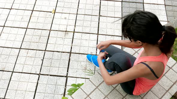 Woman tying her shoelace and sitting on chair