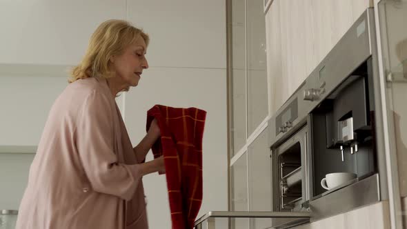 Smiling Elderly Woman Baking Pastries at Home Taking the Pastries Out of the Oven An Elderly Lady in