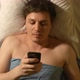 A caucasian young man types by mobile phone in a bed - VideoHive Item for Sale