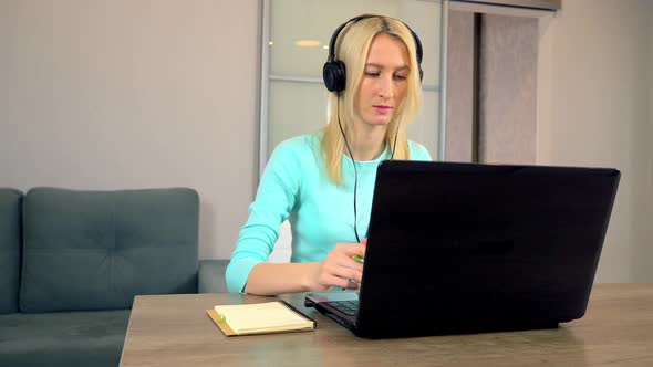 female freelancer with headphones is talking in video chat using laptop.