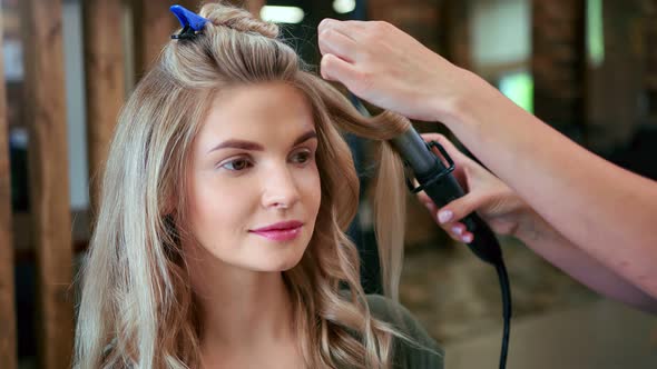 Hands of Hairdresser Creating Curly Hairstyle Use Curling Iron