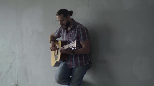 Absorbed Guitarist Standing Against Grey Wall in Underground Crossing and Playing Guitar. Portrait