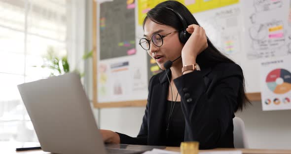 Happy female glasses wears headset video calling on laptop