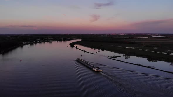 Petroleum Tanker Navigating On Ship Canal Against Hued Sunset Sky. - Aerial Wide Shot