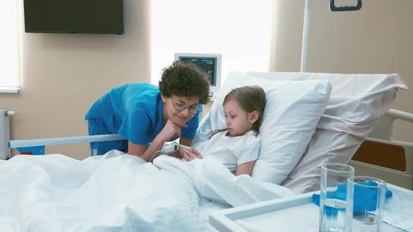 Nurse entertaining little girl in sickbed