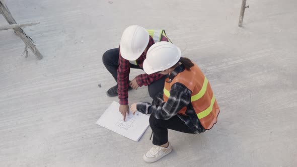 Architect and client discuss help create plan with blueprint of the building at construction site