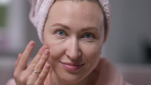 Closeup Face of Smiling Young Woman Applying Facial Cream in Slow Motion Looking at Camera