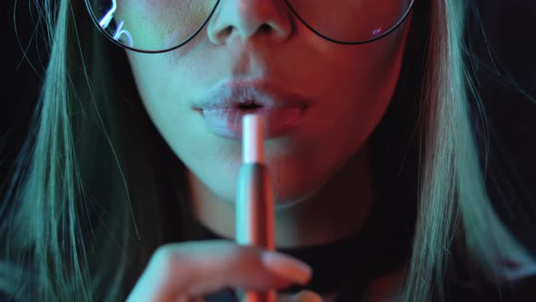 Closeup of Lips of a Young Girl Smokes an Electronic Cigarette and Release Smoke