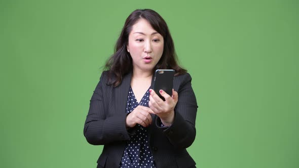 Mature Beautiful Asian Businesswoman Looking Shocked While Using Phone