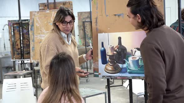 Mature latin teacher working with students inside art classroom at university