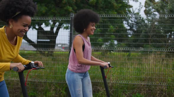 Two mixed race women riding electric scooter