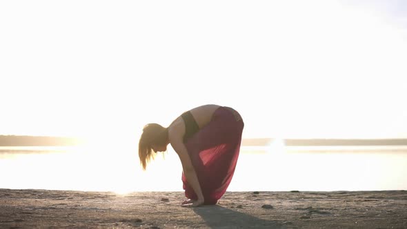 Woman in Yoga Outfit Doing Yoga on a Beach and in Front of the Water