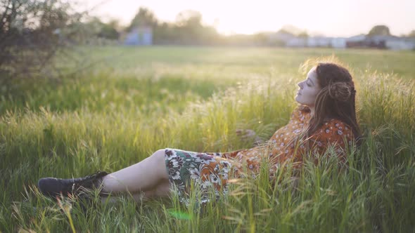 Beautiful Hippie Woman with Dreadlocks in Green Grass at Sunset Having Good Time Outdoors