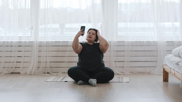 A Fat Woman Sitting on the Floor and Making a Selfie with Her Phone