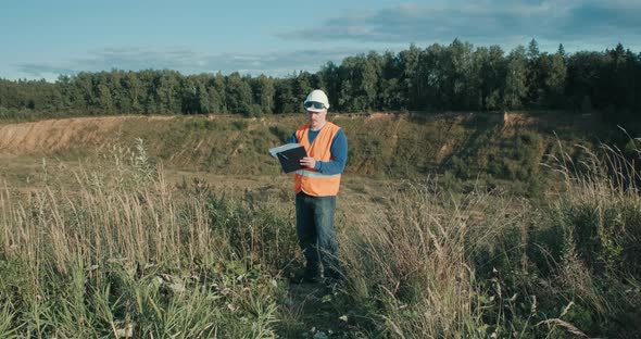 Working Engineer in Helmet Next to Sand Pit