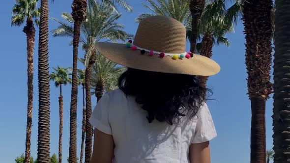 Asian woman walking down a palm tree lined path