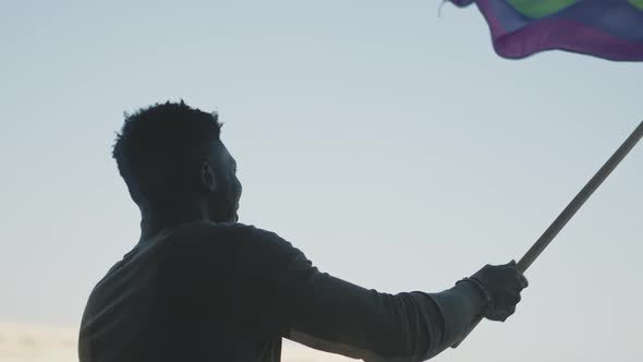 Black Man Waving Rainbow Flag Symbols Amid Protesters for LGBT Rights, Pride Events