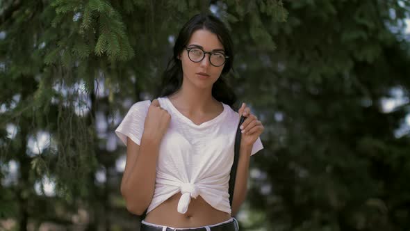 Young Woman Traveler with Backpack Standing Alone in Forest. Hipster Girl in Sunny Woods