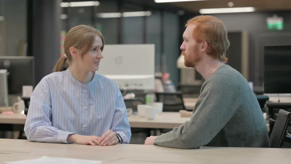 Young Man and Woman Having Discussion in Office