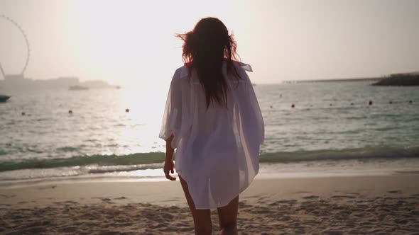 Woman in a White Shirt Walks Along the Beach of the Persian Gulf in Dubai