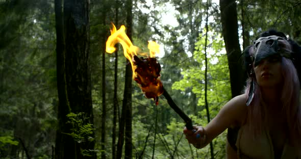 Savage Woman Is Looking Around and Hearing in Forest in Daytime, Burning Torch