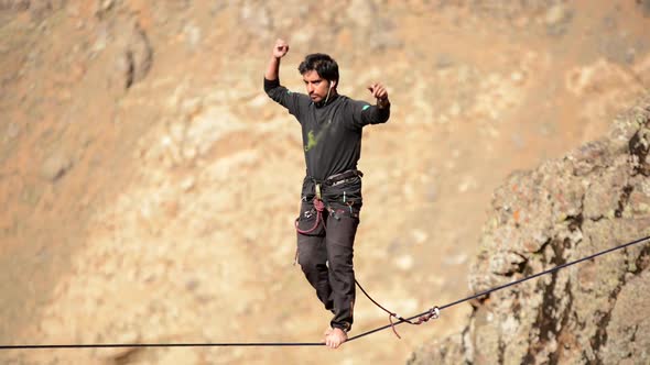 A man balances while tightrope walking and slacklining across a canyon