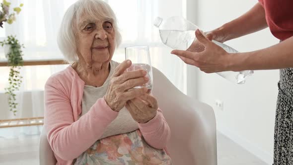 Daughter Gives Water to Elderly Mother
