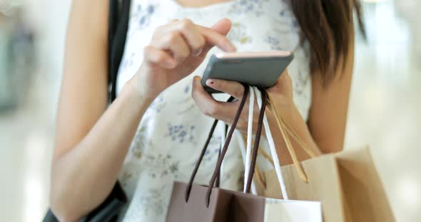 Woman using smart phone and holding shopping bag