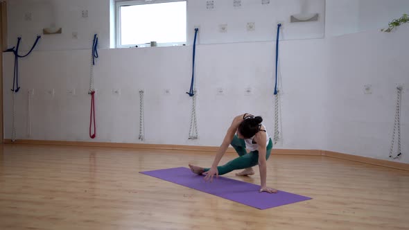 Flexible woman performing Three Legged Downward Facing Dog pose indoors