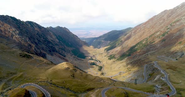 snake-shaped serpentine in the mountains, cars with a red cable car and high-voltage poles arrive