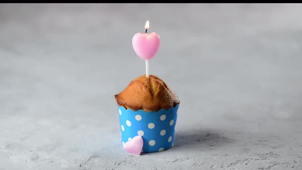 Valentines day cupcake with heart shape candle on a gray background