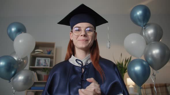 Charming Female Graduate in Academic Dress is Happily Video Chatting on Laptop During Online
