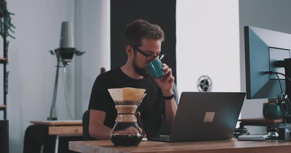 A man drinks coffee at desk