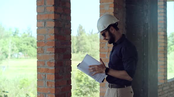 Engineer Builder In Hard Hat On Building Site. Construction Worker With Blueprints.Contractor In Hat