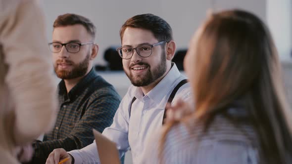 Young Happy Business Partners Talking and Smiling Behind Modern Office Table at Meeting, Listening