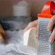 Close-up hands of mature woman is rubs a cheese on a steel grater - VideoHive Item for Sale