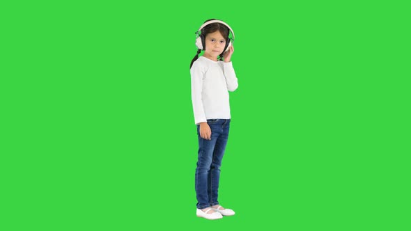 Little Girl Dressed in White Listening To the Music in Headphones and Nodding Her Head To the Rhythm