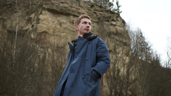 Stylish Young Guy Standing In Nature. Behind Him Is Rock.