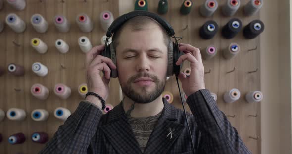 Handsome Man Listening to Music and Smiling at Camera in Atelier at Threads Set