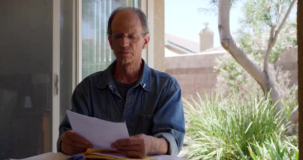 An older middle aged man reading a medical letter giving him bad news that he has been diagnosed wit