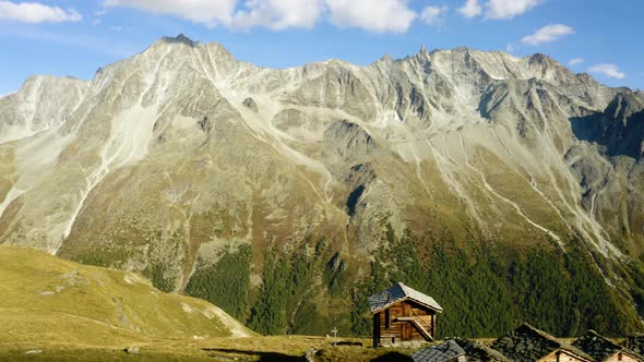 Aerial orbit around small "alpage" chalets revealing high mountain peaks in the backgroundAutumn co