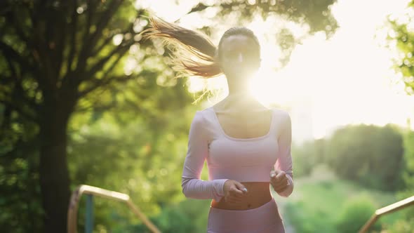 A Young Woman Runner is Training in Summer Park