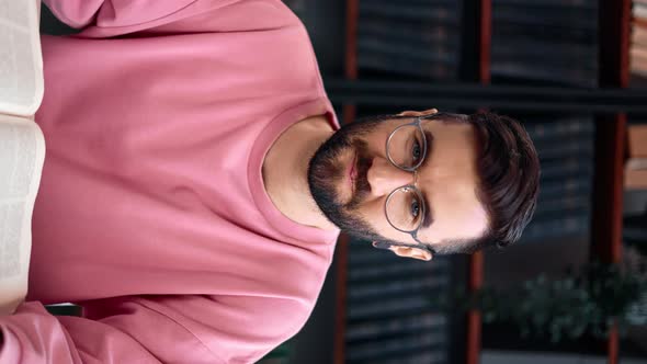 VERTICAL VIDEO POV Modern Bearded Man Friendly Smiling Reading Paper Vintage Book at Library Desk
