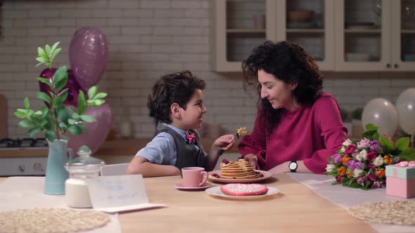 Caring Arab Son Feeding Mom with Pancakes