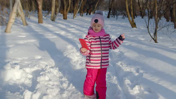 Child Girl Vlogger Making Selfies Photo for Social Networks Chatting with Friends in Winter Park