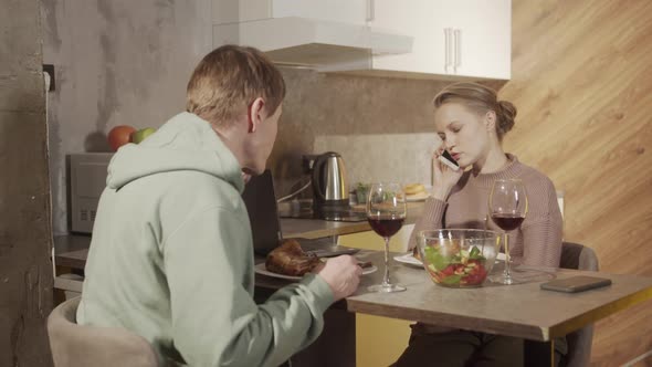 Young Wife Does Not Pay Attention To Her Husband Talking Her Smartphone During Festive Family Dinner